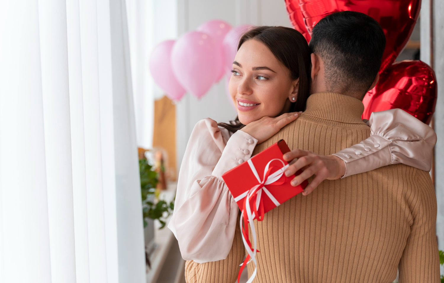 A woman hugs her partner while holding a gift.