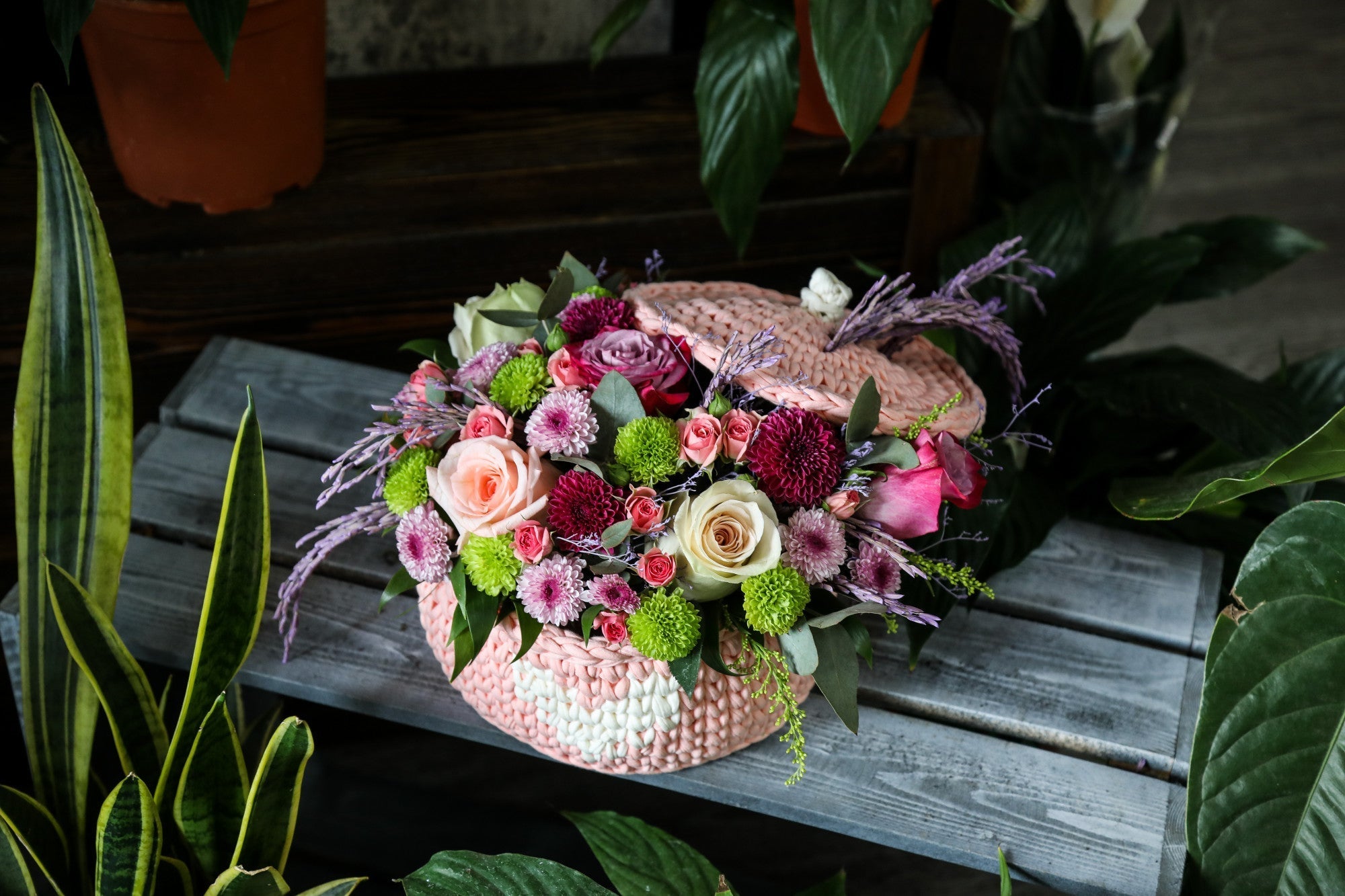 A bouquet of roses and wildflowers in a wooden basket.