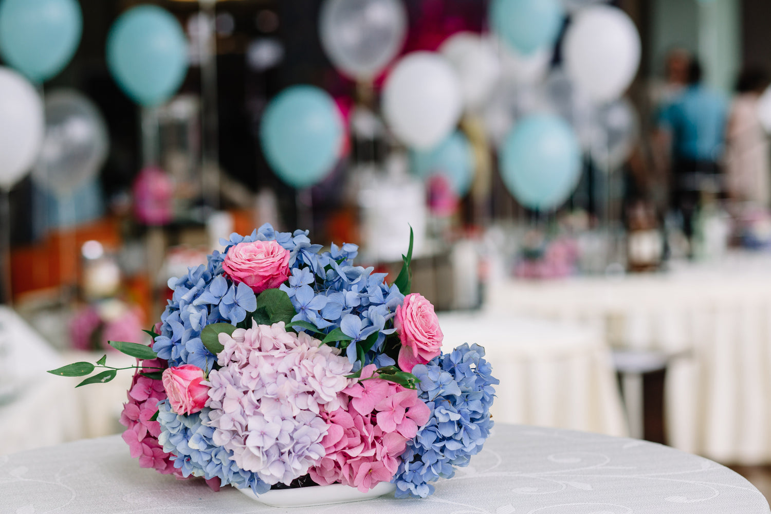 An arrangement of birthday flowers with mixed colourful blooms on a table at a party.