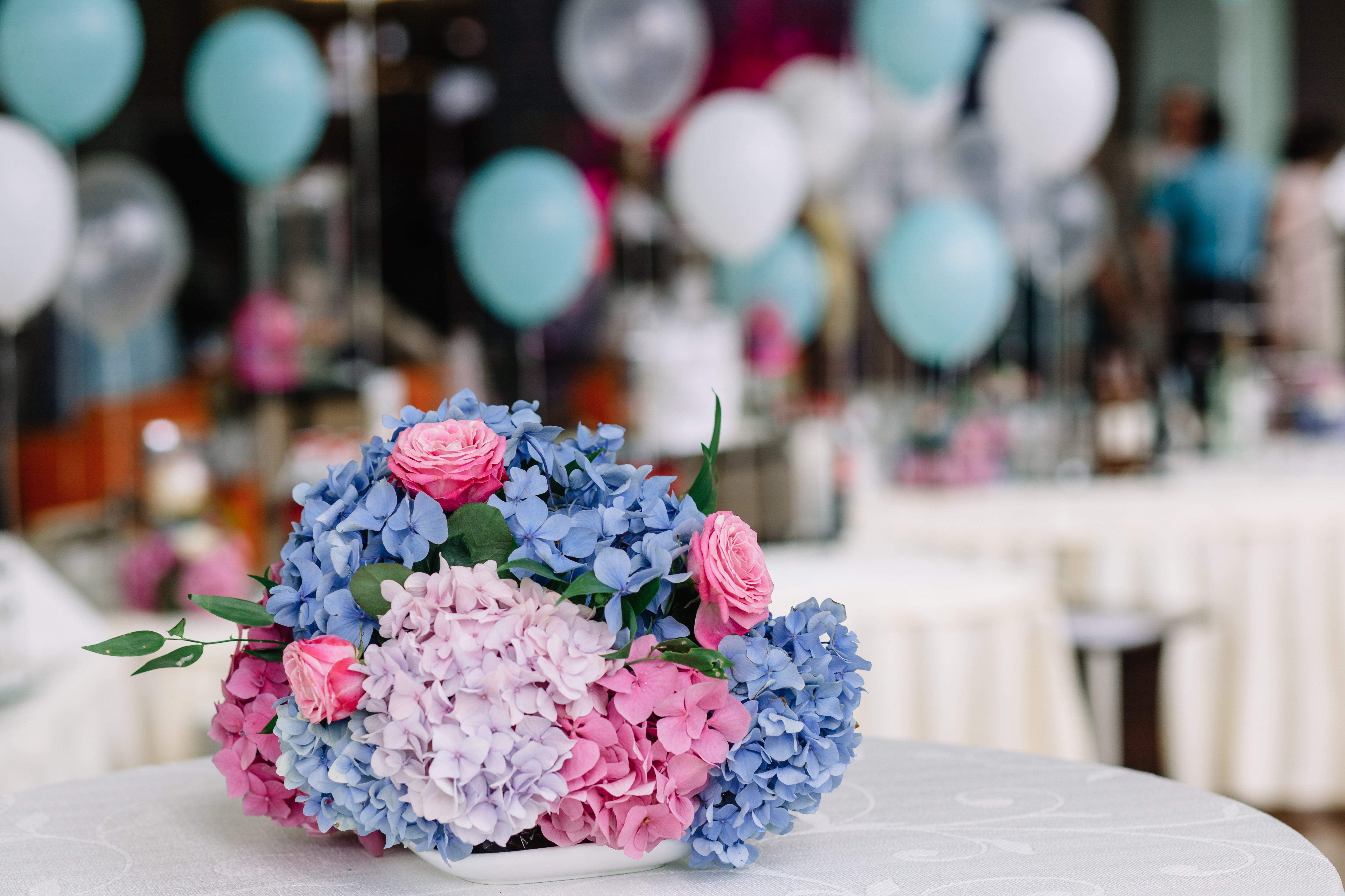 An arrangement of birthday flowers with mixed colourful blooms on a table at a party.