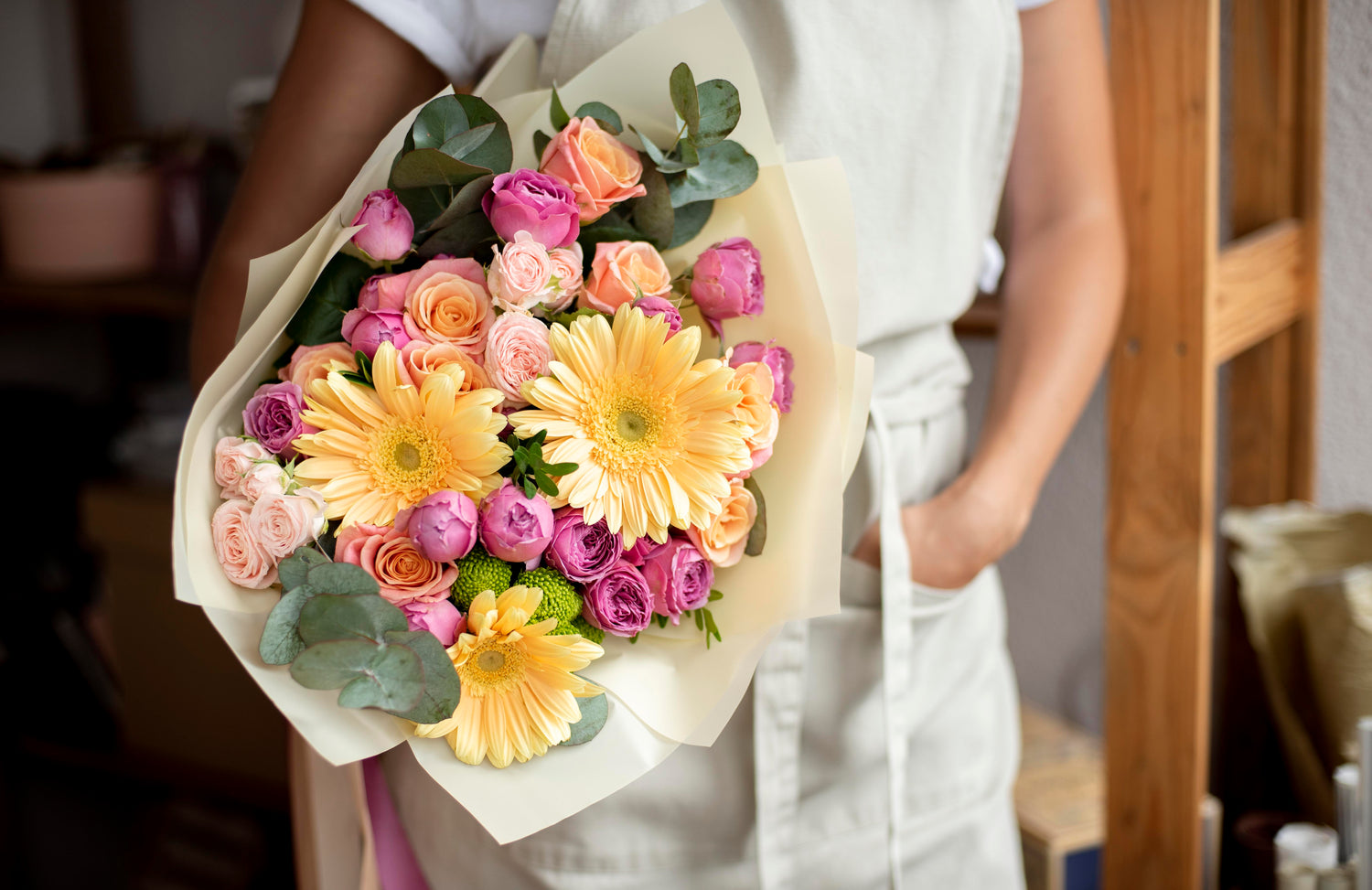 A woman holds a flower bouquet while standing.
