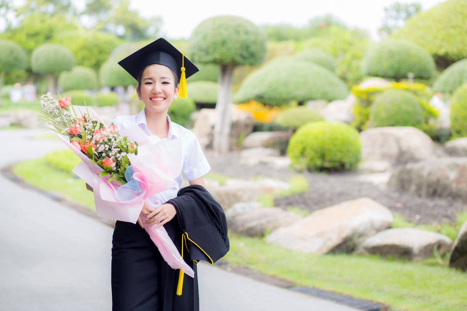A young female graduate holding a flower bouquet at her graduation.